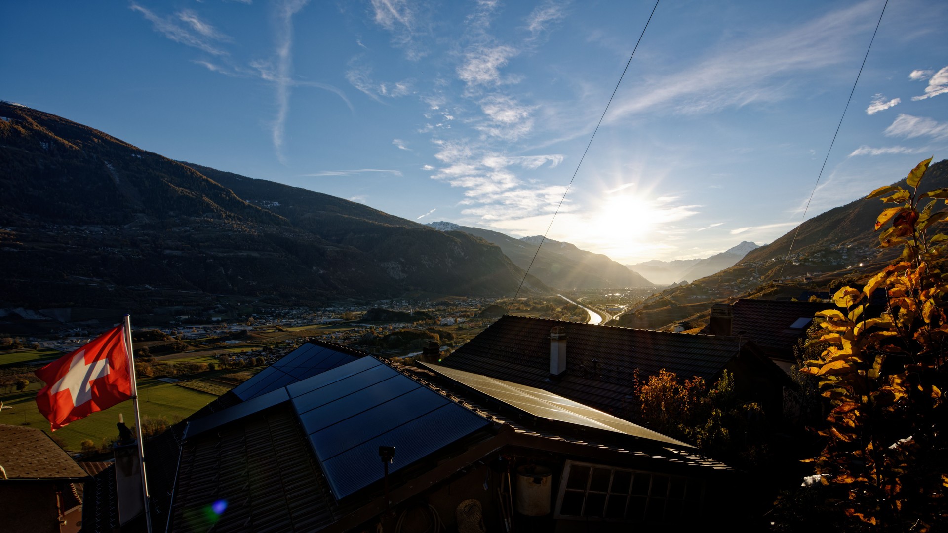 Scenic view of the Swiss Rhone Valley, Valais, with a waving Swiss flag in the foreground